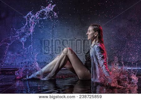 Girl In The White Shirt With Water Drop In A Dark Room Illuminated By Light During A Photoshoot With