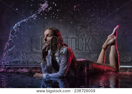 Girl In The White Shirt With Water Drop In A Dark Room Illuminated By Light During A Photoshoot With