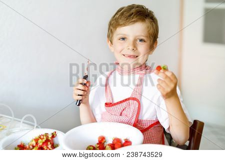 Little Blond Kid Boy Helping And Making Strawberry Jam In Summer. Funny Child Cleaning Berries And P