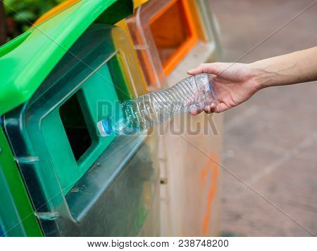 Closeup Portrait Woman Hand Throwing Empty Plastic Water Bottle In Recycling Bin.