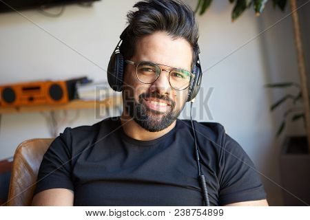 Portrait Of Smiling Bearded Man In Headphones Enjoing Listening To Music On At Home. Relaxing And Re