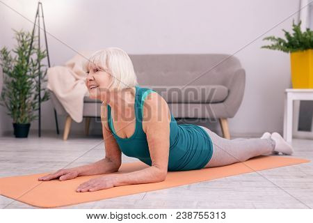 Healthy Spine. Upbeat Young Woman Lying On The Yoga Mat And Lifting Her Torso Up, Stretching The Mus