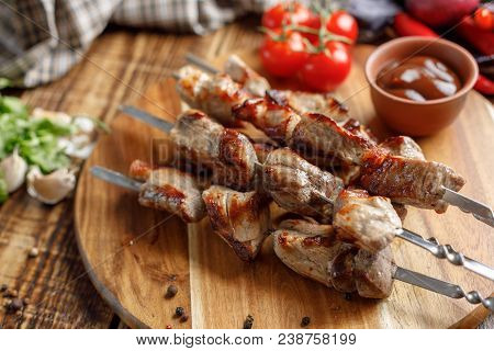 Juicy Kebabs Of Pork And Fresh Vegetables On A Wooden Background. Meat Cooked On An Open Fire. Rusti