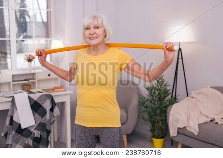 Perfect Mood. Pleasant Senior Lady Holding A Health Wand Behind Her Back And Smiling At The Camera W