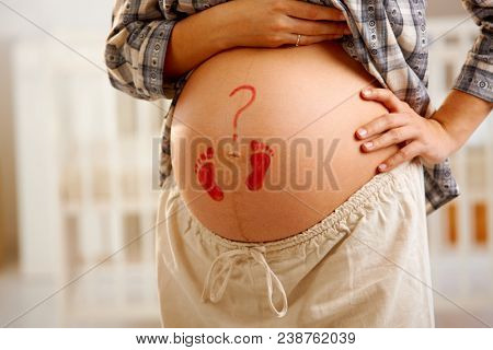 Close-up of pregnant belly with little drawn footprints and question mark.