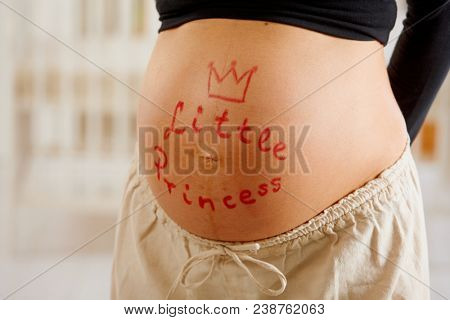Close-up of pregnant belly of mother expecting little girl.
