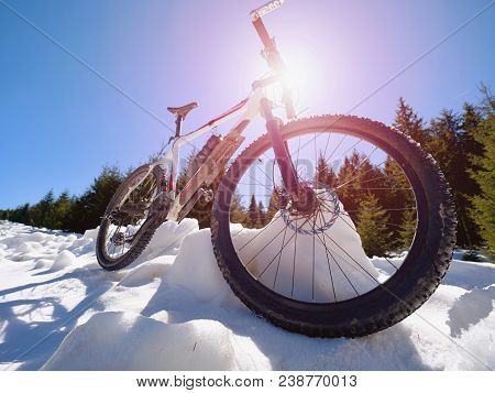 Close Wide View To Mountain Bike Stays In Snow. Winter Snowy Mountains With Road Between Trees.