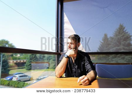Thoughtful Male Ecologist Sitting At Office On Sofa With Trees In Background. Concept Of Business An