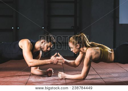 Young Athletes Giving High Five To Each Other While Doing Push Ups In Sports Hall