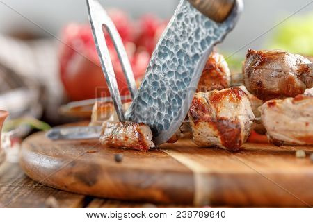Appetizing Meat Cooked On An Open Fire That Begins To Cut With An Original Knife And Fork. Cutlery F