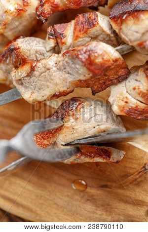 Delicious And Juicy Kebabs On Pork Skewers On A Wooden Board That Are Cut With Original Cutlery For
