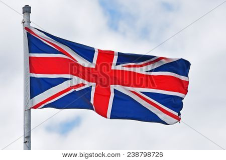 United Kindom Of Great Britain And Northern Ireland National Flag Aka Union Jack On Cloudy Sky.