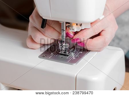 A Seamstress Puts The Needle In The Sewing Machine. Close Up