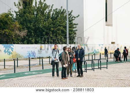 Portugal, Lisbon 29 April 2018: Tourists Or Company Of Friends Or Group Of People Walk Down By Stree
