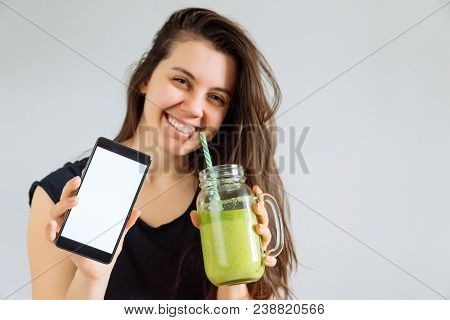 Young Pretty Woman Portrait Drink Smoothie And Show Shite Screen In Smartphone. White Background. Co