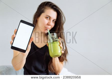 Young Pretty Woman Portrait Drink Smoothie And Show Shite Screen In Smartphone. White Background. Co