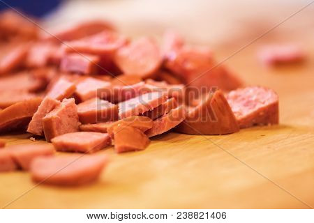 Pile Of Sliced Sausage On Wood Cutting Board.