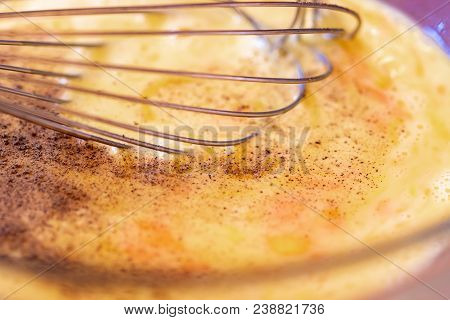 Egg Mixture In Glass Bowl With Wisk And Seasoning.