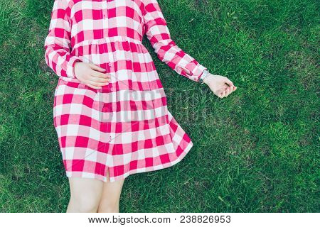 Woman Lay On Green Grass In Red Dress. Overhead View
