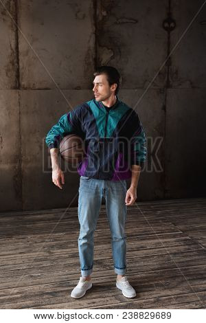 Attractive Young Man In Vintage Windcheater With Basketball Ball Looking Away