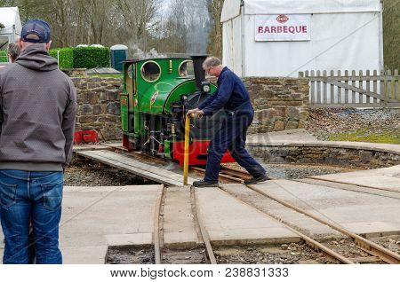 Shelley, Uk: April 8, 2018: A Man Watches From A Platform Whilst A Narrow Gauge Steam Train Is Turne