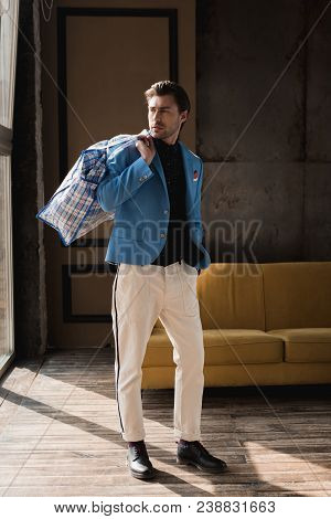 Handsome Young Man With Vintage Zippered Duffle Bag On Shoulder In Loft Interior