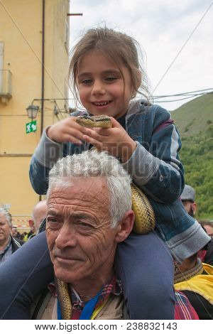 Cocullo, Italy - May 1, 2018: Beautiful Little Girl Caressing A Big Snake At The Serpari Feast In Co