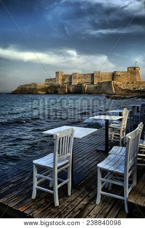 White Wooden Chairs On Bozcaada Coast And Tenedos Castle View