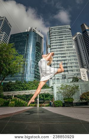 Passionate Beautiful Blonde Female Dancer Jumps High In The Air, Wearing A White Dress,