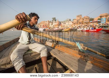 VARANASI, INDIA - MAR 26, 2018: Boatmen on a boat glides through water on Ganges river along shore of Varanasi. According to legends, Varanasi was founded by God Shiva about 5000 years ago.
