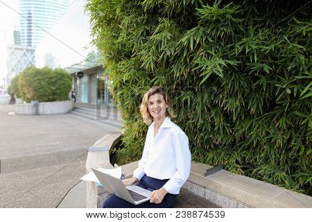Secretary Working With Laptop And Papers In Open Air Near Green Plant. Concept Of Busines, Modern Te