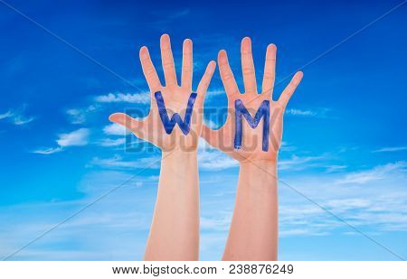 Many People Hands With Letters Building The German Word Wm Means World Cup. Blue Cloudy Sky As Backg