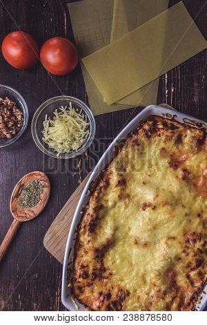 Lasagne Layered Served On A Wooden Board With Fresh Tomatoes Alongside Cheese