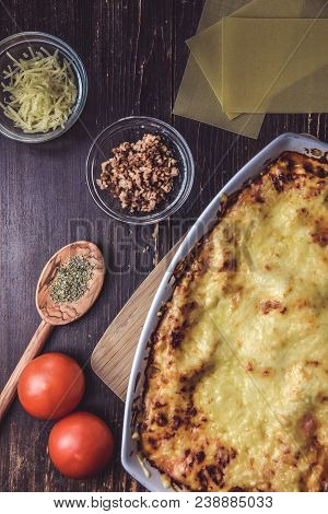 Lasagne Layered Served On A Wooden Board With Fresh Tomatoes Alongside Cheese