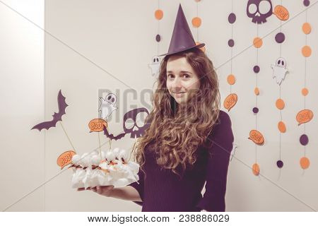 Portrait Of Charming Young Witch In Witches Hat And Black Dress At Halloween Party.  Happy Halloween