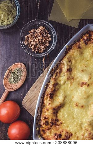 Lasagne Layered Served On A Wooden Board With Fresh Tomatoes Alongside Cheese