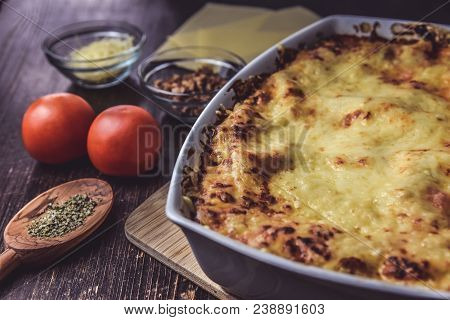 Lasagne Layered Served On A Wooden Board With Fresh Tomatoes Alongside Cheese