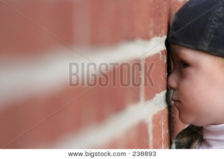 Ragazzo carino con naso schiacciata contro il muro di mattoni
