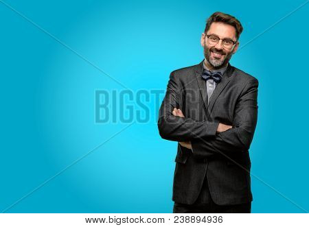 Middle age man, with beard and bow tie with crossed arms confident and happy with a big natural smile laughing