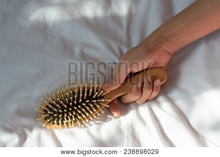 Hair Fall, Hair Loss Problem. Woman Hand Holding Comb With Hair Loss On White Bed Cover. Healthy And