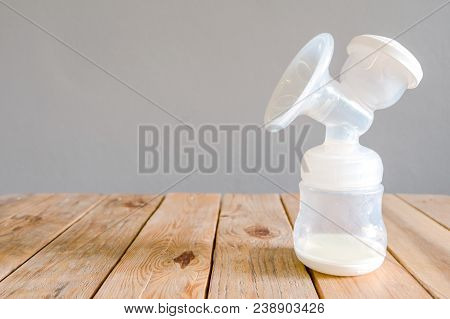 Bottle Of Automatic Pumping Breast Milk With Some Mother Milk For Baby On Wooden Table With Clipping