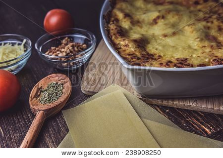 Lasagne Layered Served On A Wooden Board With Fresh Tomatoes Alongside Cheese