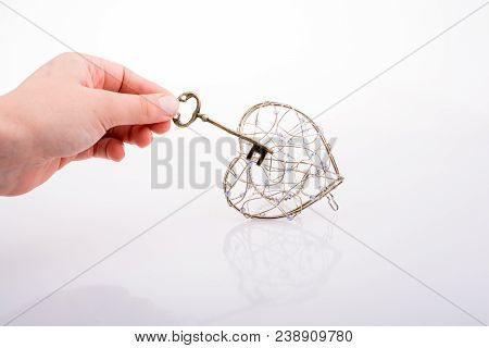 Key And A Heart Shaped Metal Cage On White