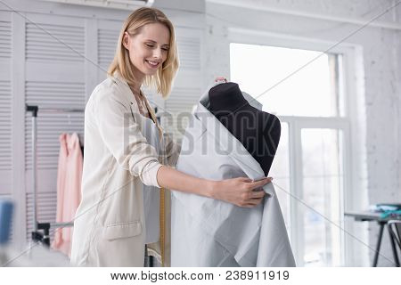 New Thinking Way. Merry Female Tailor Working With Fabric While Grinning