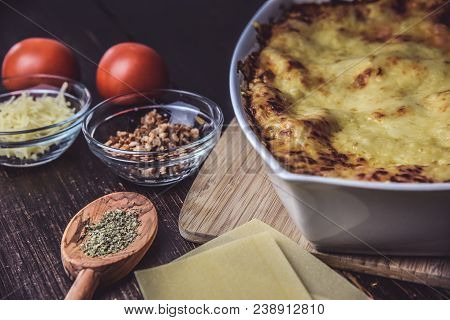 Lasagne Layered Served On A Wooden Board With Fresh Tomatoes Alongside Cheese