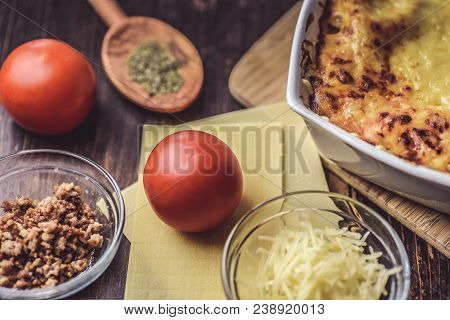 Lasagne Layered Served On A Wooden Board With Fresh Tomatoes Alongside Cheese
