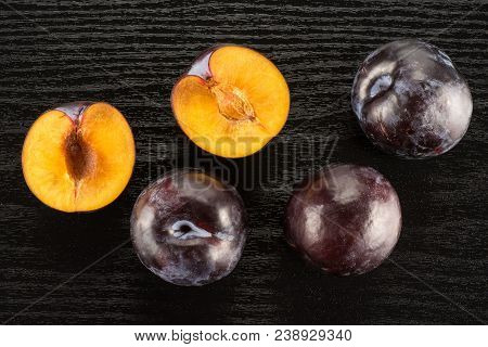 Red Blue Plums Three Whole Two Sliced Halves Table Top Isolated On Black Wood Background