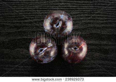 Three Red Blue Plums Table Top Isolated On Black Wood Background Round Whole Fresh Juicy Fruit
