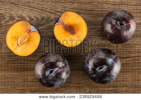 Red Blue Plums Three Whole Two Sliced Halves Table Top Isolated On Brown Wood Background
