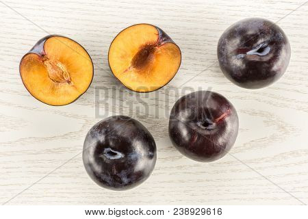 Red Blue Plums Three Whole Two Sliced Halves Table Top Isolated On Grey Wood Background